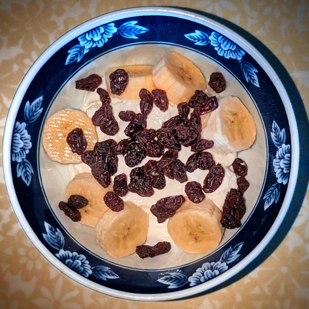 A bowl of yoghurt with banana and raisins