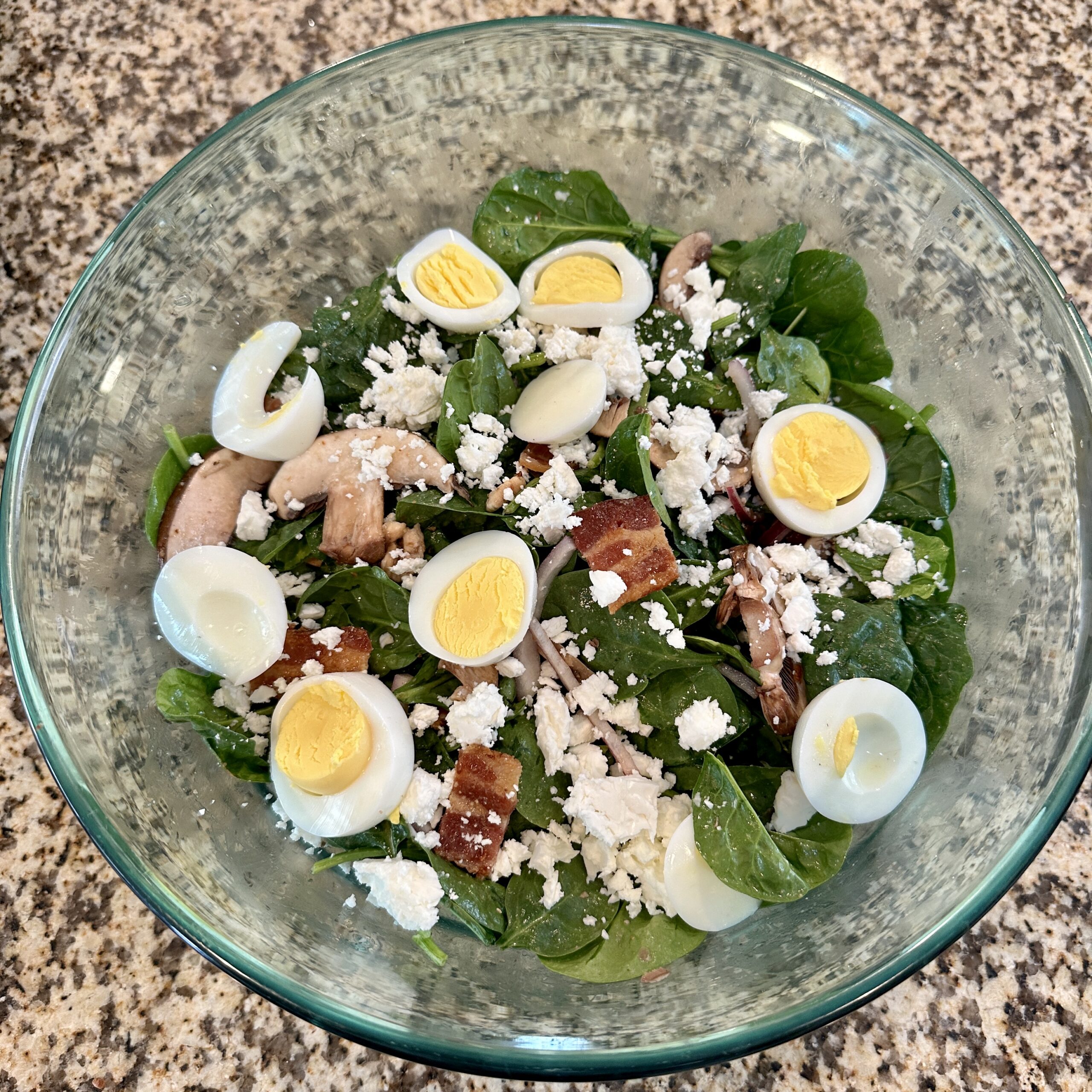 Spinach salad with bacon, mushrooms, feta, red onions, and a warm dressing